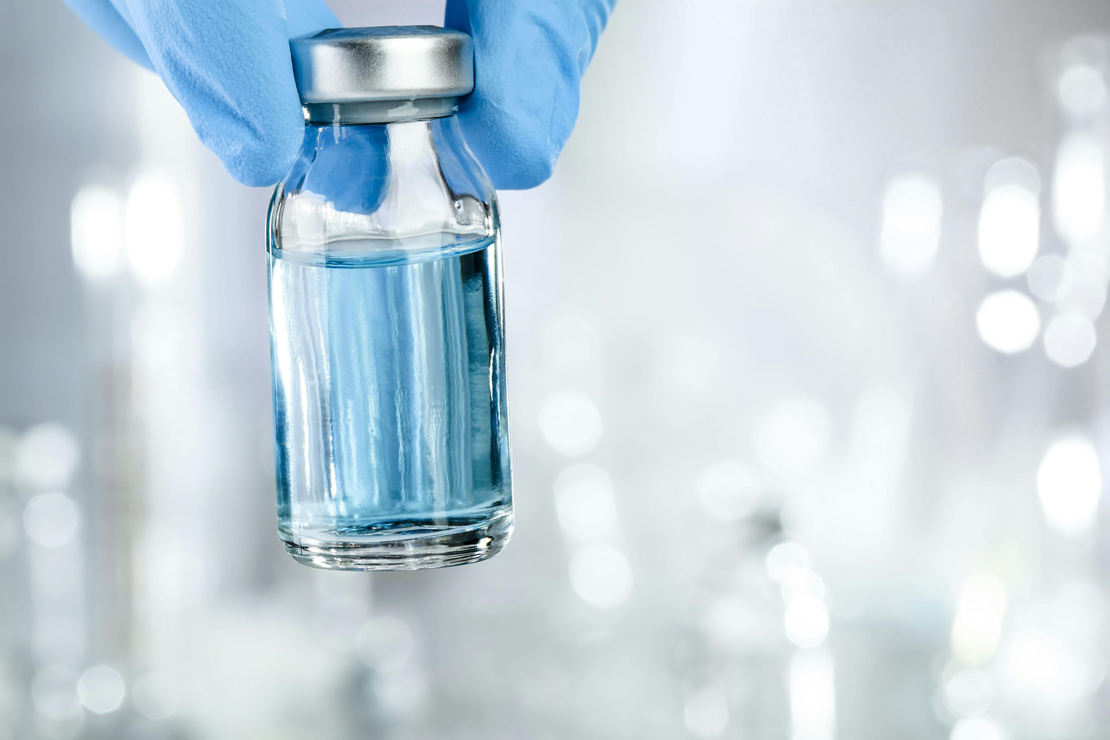 Healthcare concept with a hand in blue medical gloves holding a vaccine vial with blue liquid. Image Credit: Adobe Stock Images/Leigh Prather