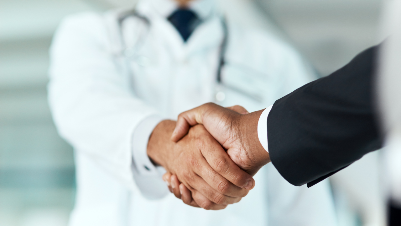 Closeup, doctor or man with handshake, negotiation or planning with partnership, healthcare or wellness. Medical professional, consultant or employee with an offer, support or teamwork with promotion.  Image Credit: Adobe Stock Images/Donson/peopleimages.com