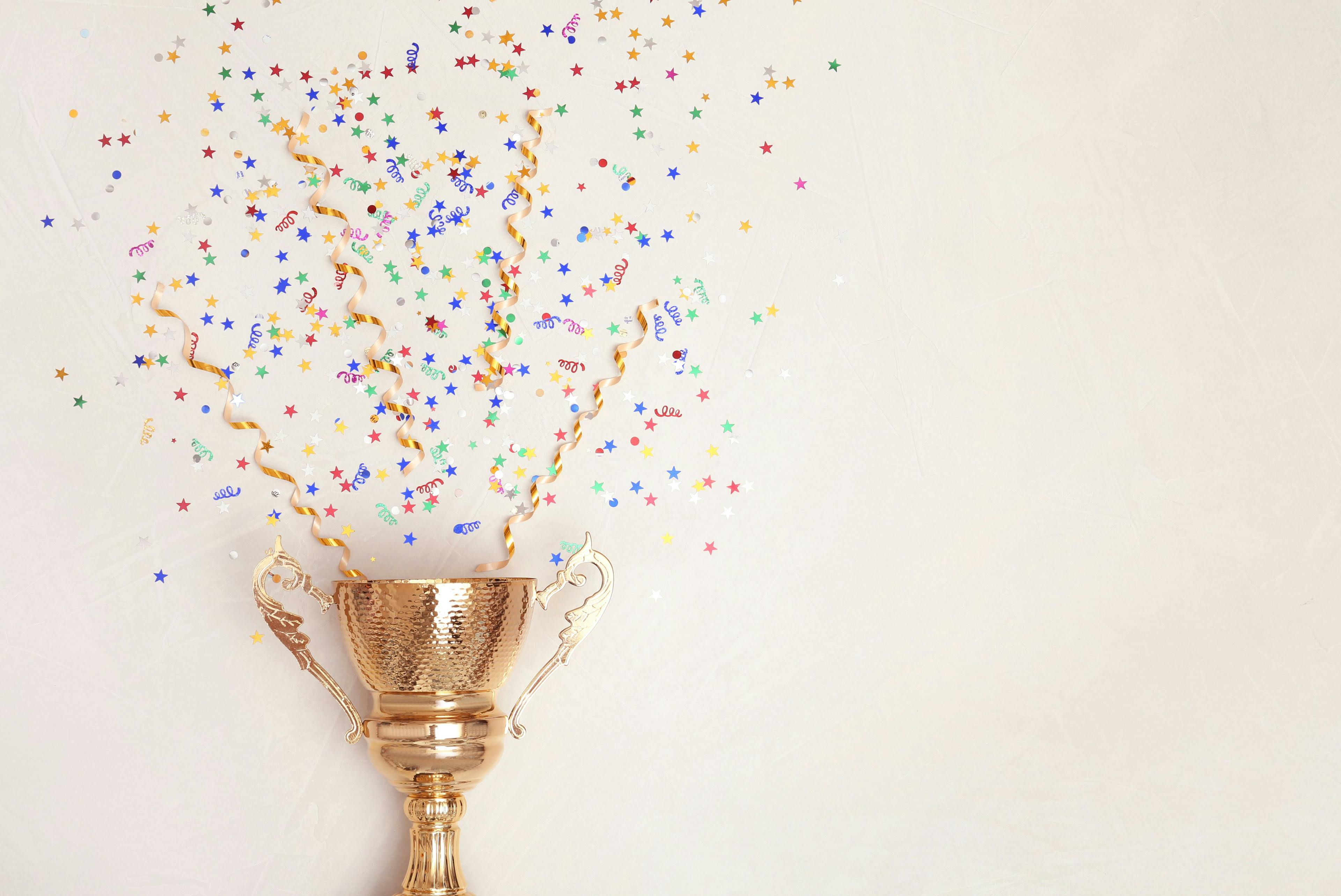 Trophy and confetti on light background, top view with space for text. Victory concept. Image Credit: Adobe Stock Images/New Africa