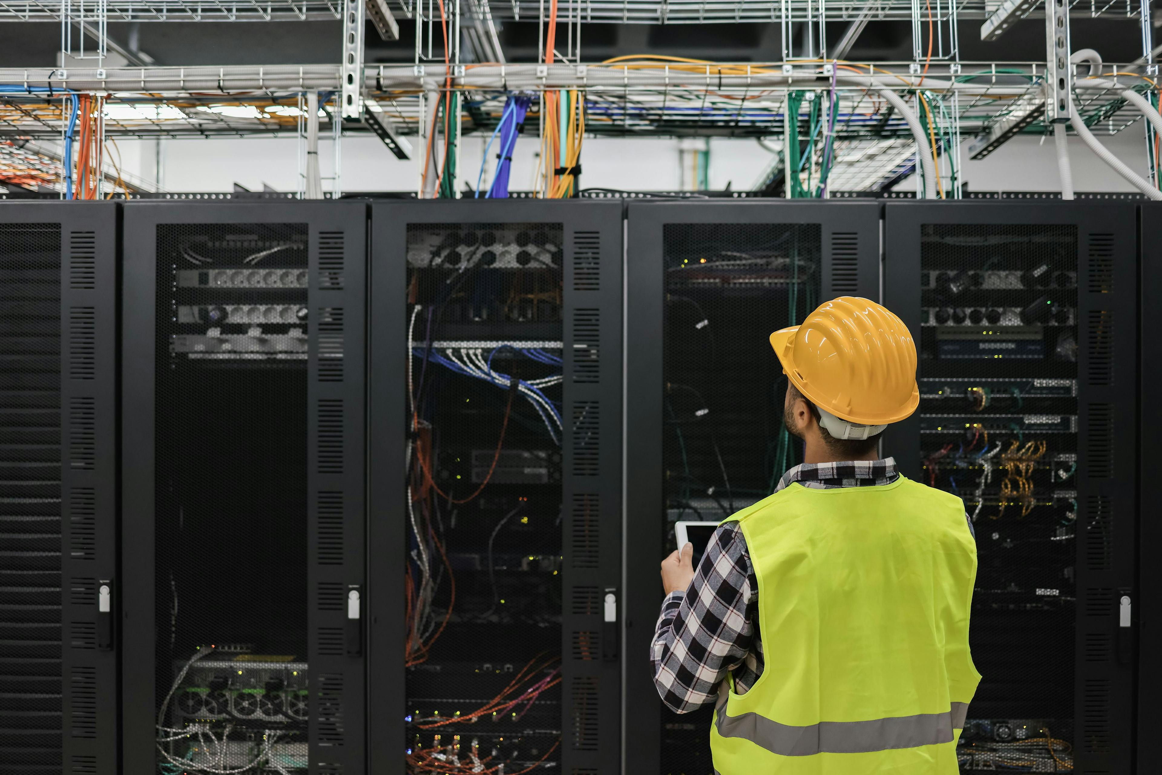 Young technician man working with tablet inside big data center room full of rack servers - Focus on man head. Image Credit: Adobe Stock Images/DisobeyArt