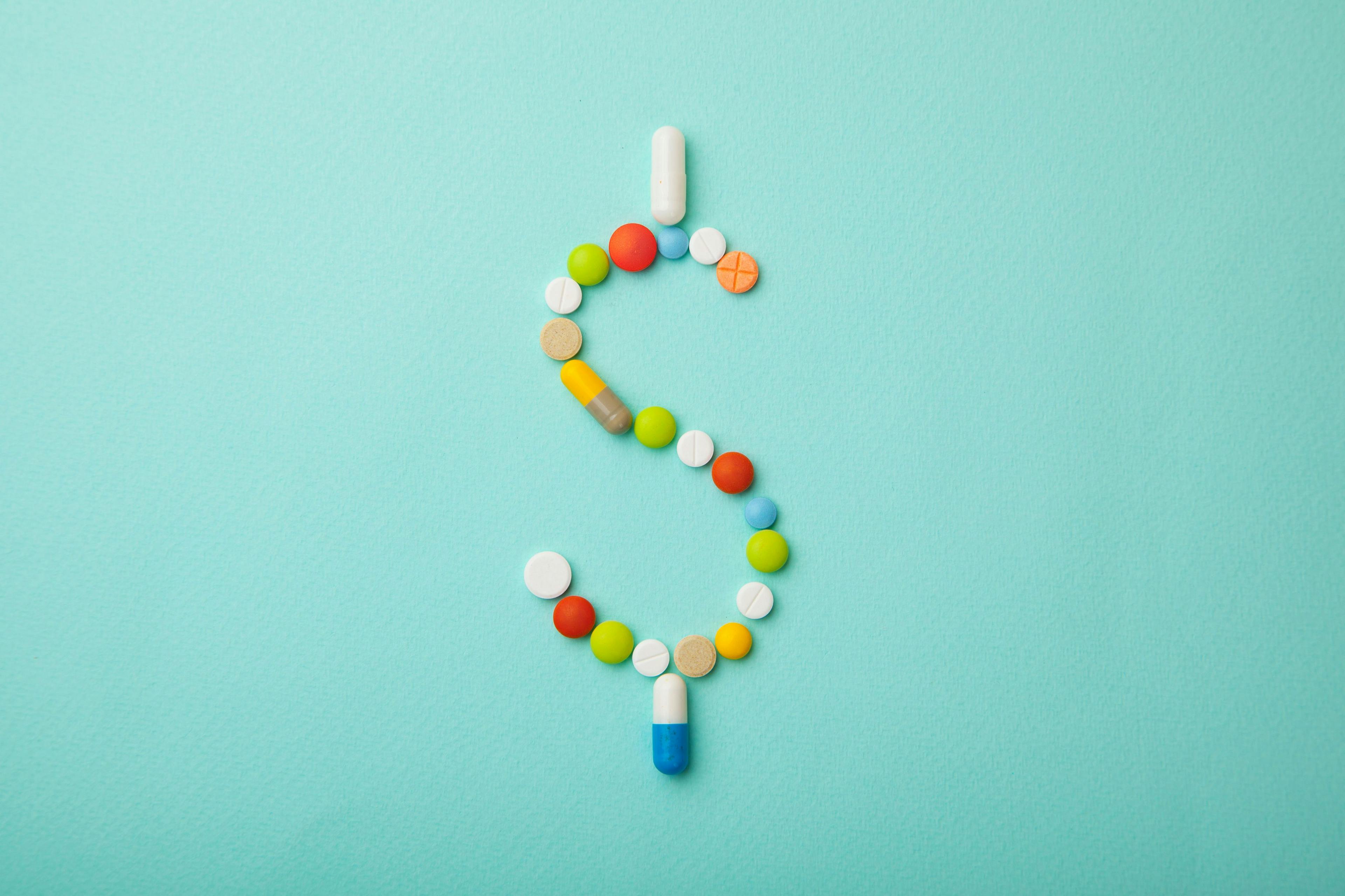 Image credit: adragan | stock.adobe.com. Symbol of money dollar from colored pills and capsules on green background. Expensive medicine and medical insurance